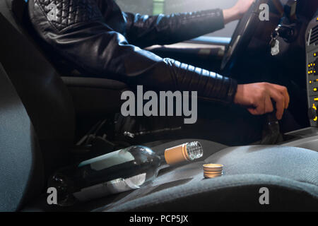 Betrunkener junge Mann mit leeren Alkoholflaschen auf Badezimmerboden