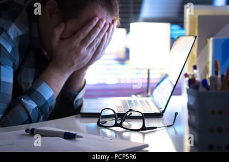 Probleme bei der Arbeit. Traurig, unglücklich und müde Mann für Gesicht mit den Händen im Büro oder zu Hause in der Nacht. Burnout, Stress, Mobbing oder Depressionen. Stockfoto