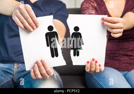 Trennung, Scheidung und Eheprobleme Konzept. Paar hält riss ein Stück Papier mit Mann und Frau Symbol. Stockfoto