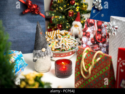 Weihnachten Dekorationen und Geschenke auf dem Tisch. Little Santa Claus, Weihnachtsbaum, Kerzen und Lebkuchen. Urlaub noch leben Layout. Stockfoto