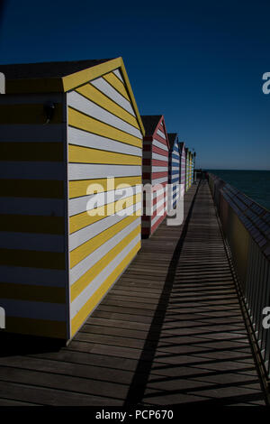 Bunt gestreiften Strand Hütten auf der Pier von Hastings, East Sussex, England Stockfoto