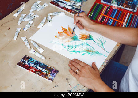 Hände von Künstlerin Blumen malen mit Aquarellfarben und Buntstiften in art Studio. Lifestyle und Hobby Konzept Stockfoto