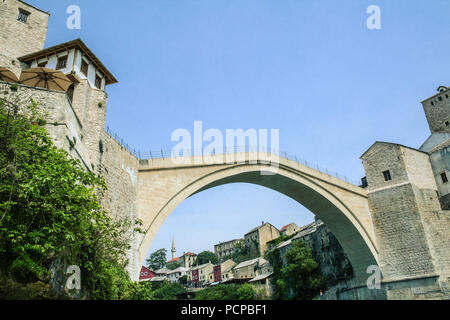 Alte Brücke von Mostar an einem sonnigen Nachmittag, mit der alten Stadt im Hintergrund sichtbar. Die Brücke ist das Symbol der vom Krieg zerrissenen Stadt Ihr Stockfoto