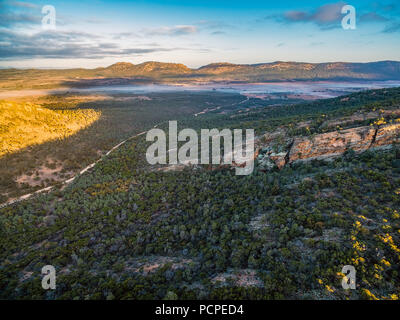 Schmutz der Straße schlängelt sich durch Hügel und die einheimische Vegetation bei Sonnenaufgang - Flinders Ranges, South Australia Stockfoto