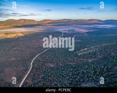 Luftaufnahme der Schmutz der Straße schlängelt sich durch Südaustralische Outback Landschaft bei Sonnenaufgang. Stockfoto