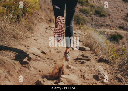 Frau runner Beine laufen auf Mountain Trail. Füße der Frau Läufer laufen über Steine auf Mountain Trail. Stockfoto