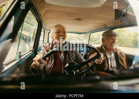 Freundliche alte Paar Fahren in einem Auto. Genießen road trip. Senior woman-driving-Auto mit Frau genießt die Fahrt und Lachen. Stockfoto