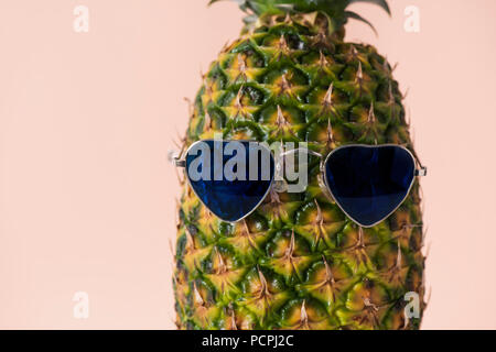 Nahaufnahme einer Ananas tragen ein Paar der herzförmigen Sonnenbrille auf eine blass rosa Hintergrund Stockfoto