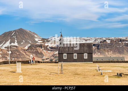 16. April 2018: Budir, Halbinsel Snaefellsnes, West Island - Das kleine Schwarze Kirche, und eine Familie von Touristen besucht. Stockfoto