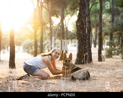 Junge attraktive Latin Frau Lehr- und liebevoll ihre schönen niedlichen Deutscher Schäferhund im Park beim Sonnenuntergang in der Natur pflege Unterstützung Glück peacefu Stockfoto