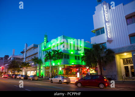 MIAMI - ca. Januar 2018: Autos fahren vorbei an berühmten Art déco-Hotels und Leuchtreklamen an der Collins Avenue in South Beach bei Nacht. Stockfoto