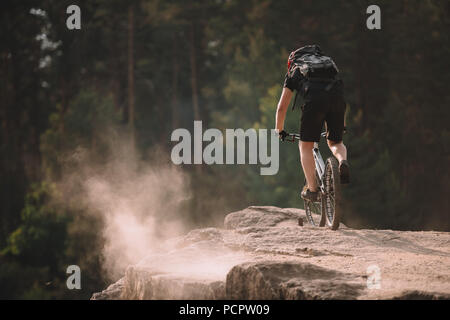 Ansicht der Rückseite des jungen Trial Biker reiten auf Felsen im Freien Stockfoto