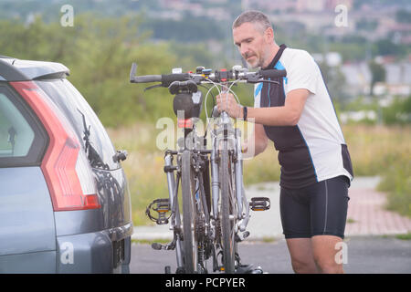 Mann, Sportswear laden Fahrräder auf dem Bike Rack zu einem Auto Anhängerkupplung montiert Stockfoto