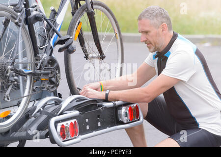 Mann, Sportswear laden Fahrräder auf dem Bike Rack zu einem Auto Anhängerkupplung montiert Stockfoto