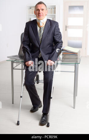 Geschäftsmann am Arbeiten tragen Nackenschutz mit Krücken Stockfoto