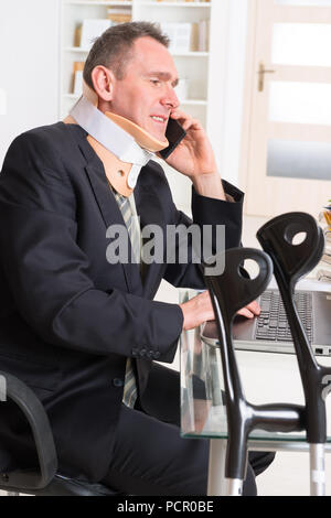 Geschäftsmann am Arbeiten tragen Nackenschutz mit Krücken Stockfoto
