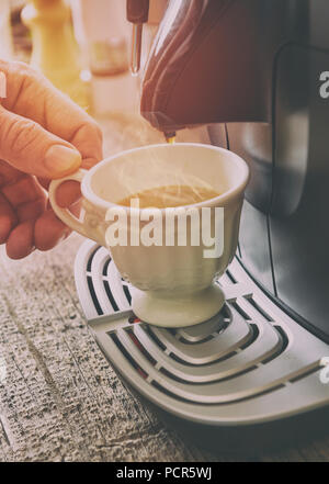 Kaffeemaschine und Hand, denn frischen Kaffee mit sichtbarer Dampf über Cup. Stockfoto
