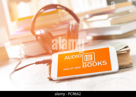 Smart Phone mit Audio Bücher Anwendung auf dem Bildschirm, der Kopfhörer und des Bücher aus Papier. Konzept der Hörbücher zu hören. Stockfoto