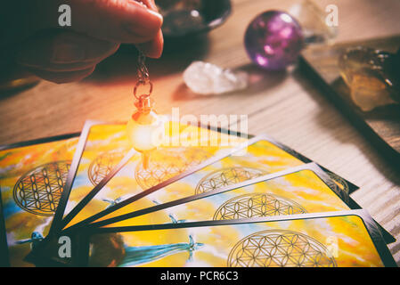 Tarot Karten wünschelrute Werkzeug in der Hand und Kristalle als ein Konzept der psychischen Advisor oder Möglichkeiten der Weissagung Stockfoto