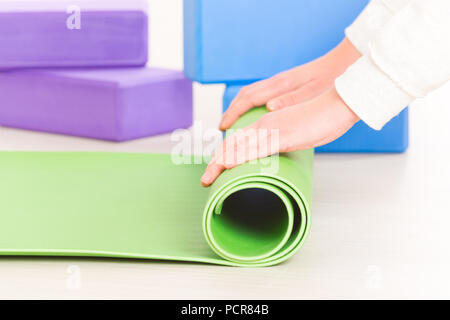Einrollen eine Yoga Matte am Boden Stockfoto