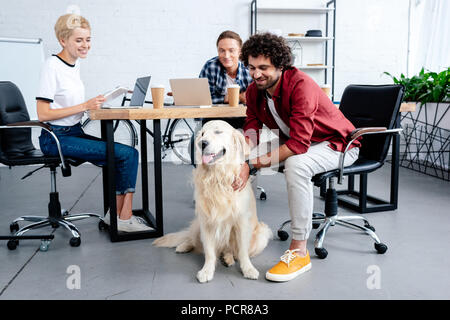 Lächelnden jungen Geschäft Leute an Hund suchen, während im Büro arbeiten Stockfoto