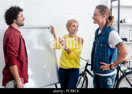 Lächelnden jungen Kollegen in der Nähe von Whiteboard und diskutieren neue Projekt Stockfoto