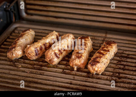 Cevapcici gebacken auf dem Grill. Kleine Würstchen aus Hackfleisch/Faschiertem, ein sehr beliebtes Gericht in den Balkanländern. Stockfoto