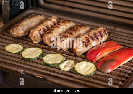 Cevapcici gebacken auf dem Grill. Kleine Würstchen aus Hackfleisch/Faschiertem, ein sehr beliebtes Gericht in den Balkanländern. Stockfoto