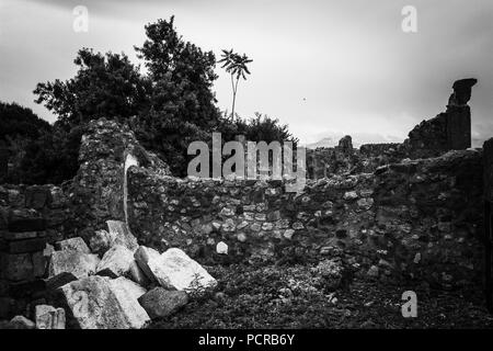 Ruinen eines alten Hauses in Pompeji, in der Nähe von Neapel, Italien, mit der Wolke auf den Vesuv im Hintergrund Stockfoto