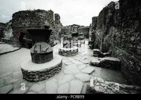 Mühlen und eine gemauerte Lehmofen im Haus der Bäcker, der Casa del Forno, einer alten Bäckerei in der antiken Stadt Pompeji, in der Nähe von Neapel, Italien Stockfoto