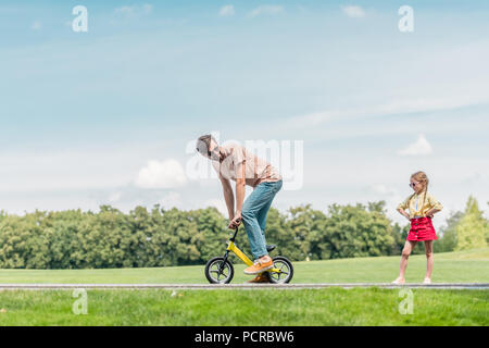 Vater reiten kleines Fahrrad und Suchen an der kleinen Tochter auf Taille Stockfoto