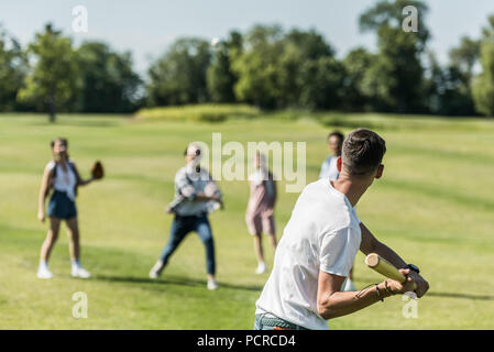 Teenage boy Holding bat und Baseball zu spielen, mit Freunden im Park Stockfoto