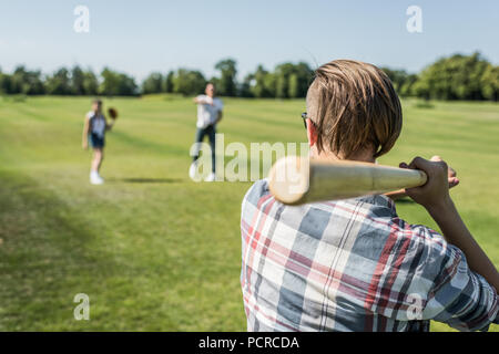 Rückansicht der Teenager Junge spielt Baseball mit Freunden im Park Stockfoto