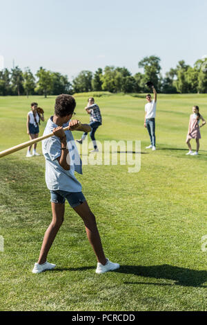 Afrikanische amerikanische Junge spielt Baseball mit jugendlichen Freunde im Park Stockfoto