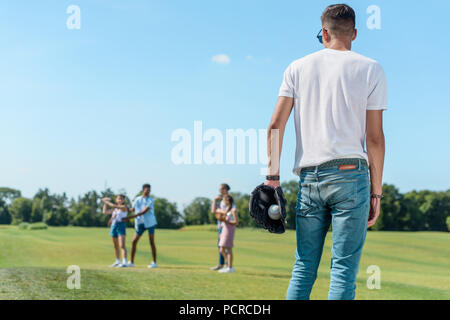 Rückansicht der Teenager Junge spielt Baseball mit Freunden im Park Stockfoto