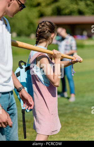 Teenage girl Holding Baseball Schläger und spielen mit Freunden im Park Stockfoto