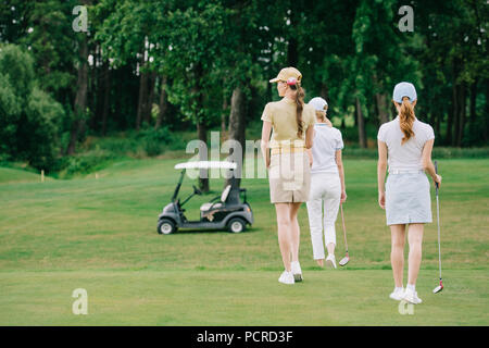 Zurück Blick auf Frauen mit Golf gear Wandern auf grünen Rasen am Golfplatz Stockfoto