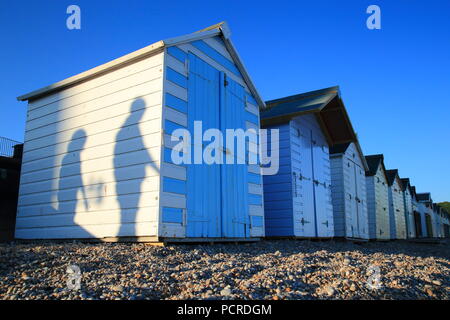 Schatten der Passanten weißen Strand Hütten im Küstenort Seaton in East Devon Stockfoto
