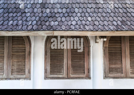 Wand im Cafe mit hölzernen Fensterläden Windows unter Ziegeldach Stockfoto