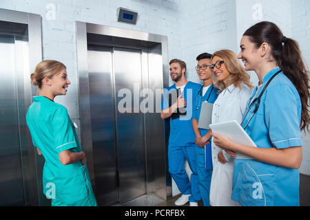 Lehrer mit multikulturellen Studenten warten, Aufzug an der Medizinischen Universität Stockfoto