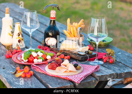 Italienisches Picknick mit Rotwein, Parmesan, Schinken und Oliven. Mittagessen im Freien. Traditionelle Snacks. Speicherplatz kopieren. Stockfoto