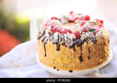 Honig Kuchen, mit Beeren und Schokolade dekoriert. süsse Familie Abendessen. Urlaub Kuchen. Auf dem Balkon Frühstück Stockfoto