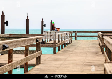 Meditieren einzelner Mann auf der Pier, die Küste der Deutschen Kolonialstadt Swakopmund, Namibia Stockfoto