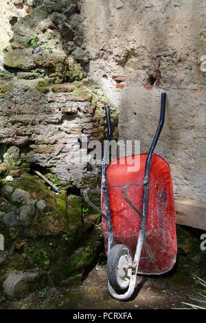 Rustikal rot Rad burrow wieder Ruhe ein Stein Garten Wand Stockfoto