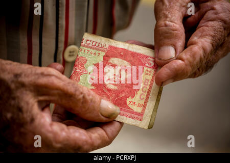 Alte kubanische Mann hält drei peso Banknote mit dem Portrait von Ernesto Che Guevara in der Hand, lokale Währung, Tasse, Kubanische Peso, Armut, La Habana, Havanna, La Habana, Kuba, Kuba Stockfoto