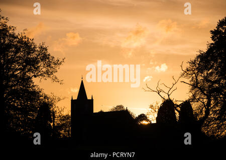 Die Silhouette eines Kirchturms und Bäume bei Sonnenuntergang in der Nähe der breiten Wasser, Moira, County Down Stockfoto