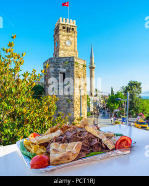 Die heiße und leckere Döner in Open Air Terrasse der traditionellen Turkeish Restaurant mit Blick auf den alten Uhrturm auf Hintergrund, Antalya, Tu Stockfoto