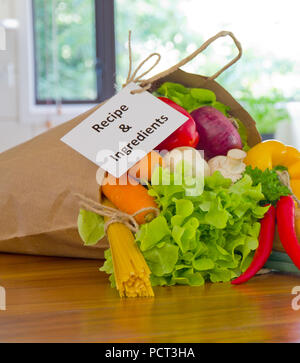 Frische Organische rohes Gemüse essen Lieferung in Papiertüte auf holzbank in der Küche Stockfoto