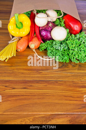 Frische Organische rohes Gemüse essen Lieferung in Papiertüte auf holzbank in der Küche Stockfoto