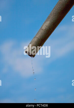 Tropfen Wasser aus Rohr - Nahaufnahme mit blauem Himmel. Konzept für die Wassermangel- und Umweltfragen. Kopieren Sie Platz zum Schreiben. Stockfoto